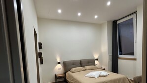 A modern bedroom with a bed, bedside tables, and a window. - Somnia Luxury Rooms  (Naples)