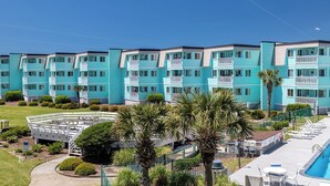 A multi-story hotel with a consistent turquoise facade, a swimming pool, and a well-maintained garden area. - SeaSpray 312, Oceanview Condo in Atlantic Beach, NC! (Atlantic Beach)