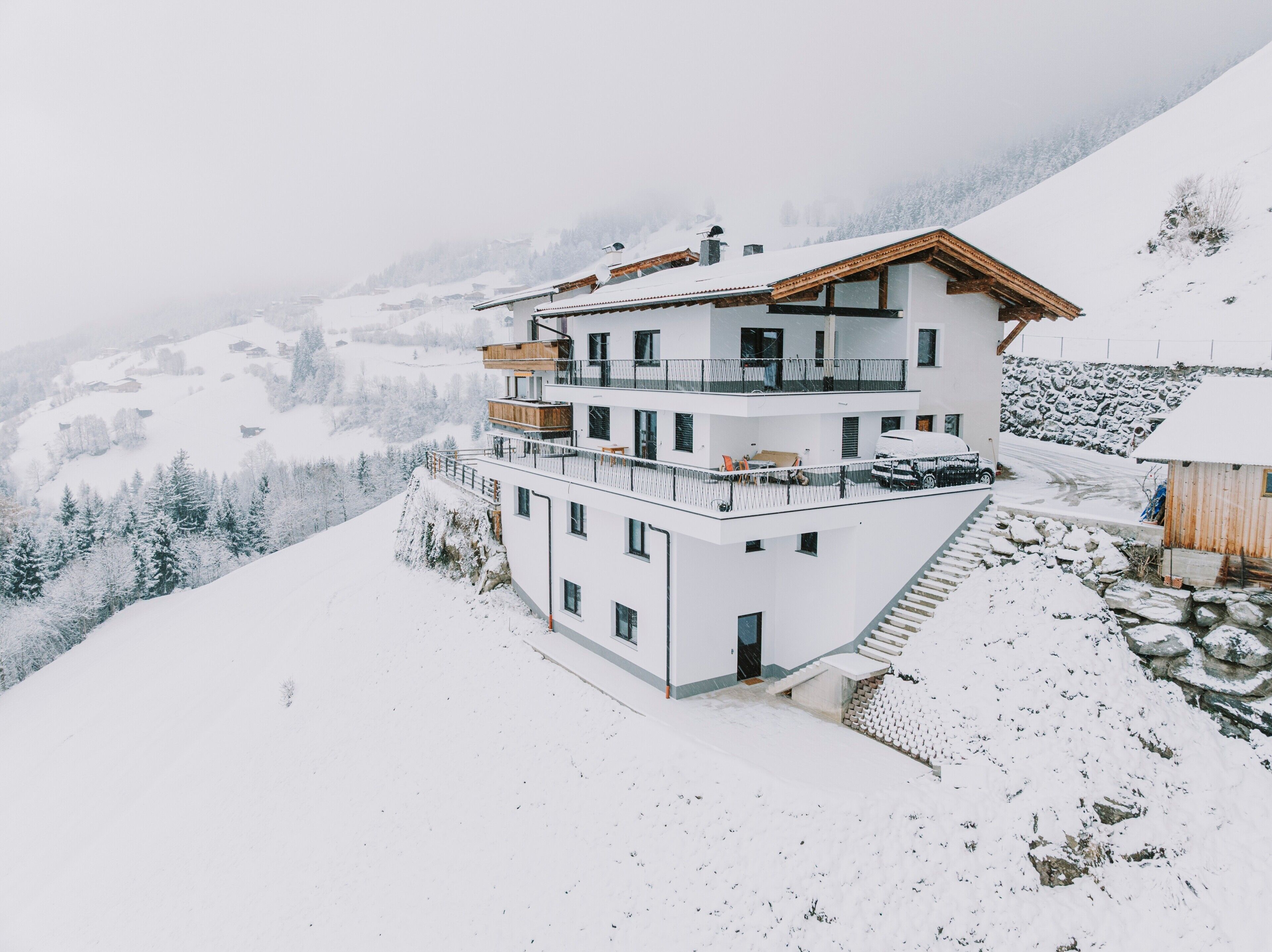 Un edificio de varios pisos con balcones, una escalera y vistas a montañas nevadas.