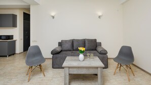 A modern living room with a grey sofa, two grey armchairs, a wooden coffee table, and a vase with yellow flowers. - Apartment by Luxe Group XO222 (Yerevan)