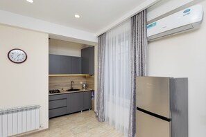 Une cuisine moderne avec des meubles gris, un réfrigérateur en acier inoxydable, une horloge et un climatiseur.