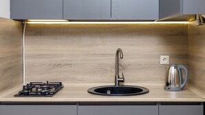 A modern kitchen with a gas stove, sink, and kettle. - Apartment by Luxe Group XO222 (Yerevan)