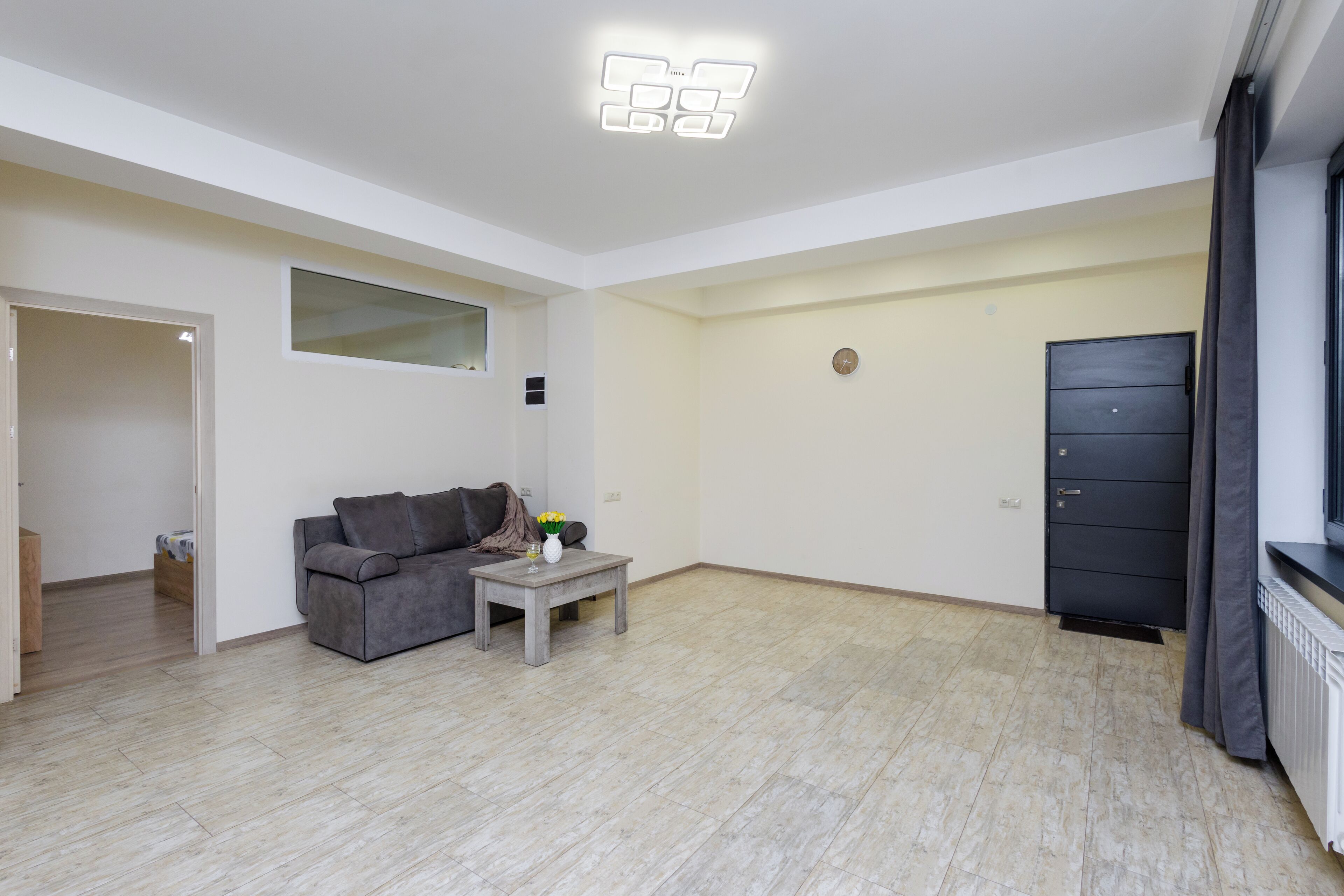 Un salon moderne avec un canapé gris, une petite table basse et un meuble noir.