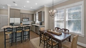 A modern kitchen with a central island, bar stools, and a dining table with chairs. - 2 Pools 1 heated, Private Beach Access, New Shops & Restaurants! NEW LISTING! (Santa Rosa Beach)