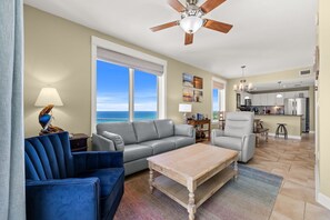 A living room with a gray sofa, blue armchairs, a wooden coffee table, and a view of the ocean through large windows. - PET FRIENDLY!!GORGEOUS 3BDR WITH GULF VIEWS!!! (Panama City Beach)