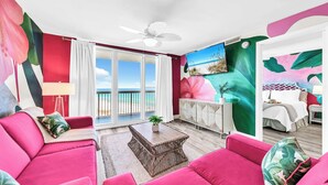 Ein Zimmer mit Balkon, einem Bett, einer Couch und einem Essbereich.