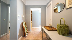 A hallway with a white bench, a wicker basket, and a mirror on the wall.