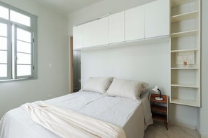 A bedroom with a bed, a nightstand, a lamp, and built-in storage cabinets. - Loft Perto do Metr e da Pra a da Rep Blica (São Paulo)