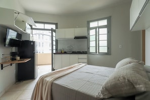 A compact bedroom with a bed, a TV, and a kitchenette. - Loft Perto do Metr e da Pra a da Rep Blica (São Paulo)