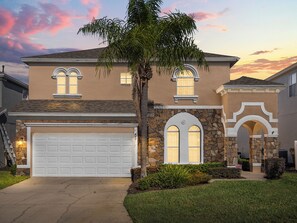A two-story house with a stone facade, a garage, and a well-maintained lawn. - Soaking up The Sun Retreat 462CP Specials (Davenport)