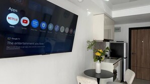 Una sala de estar moderna con un televisor de pantalla plana grande montado en la pared, mostrando varias aplicaciones.