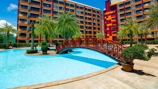 Un hotel con piscina, palmeras y un puente rojo.