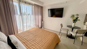 Una habitación de hotel con una cama, televisión, escritorio y silla.
