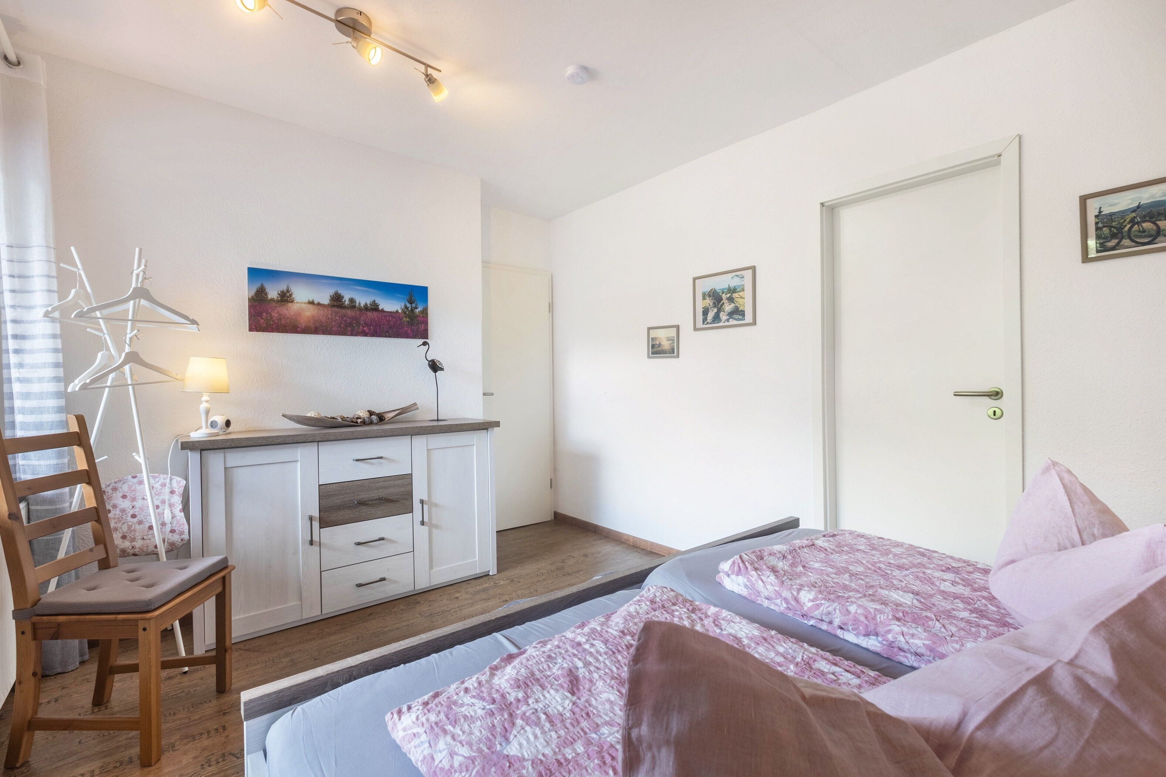 Une chambre avec deux lits, un bureau, une chaise et une fenêtre.