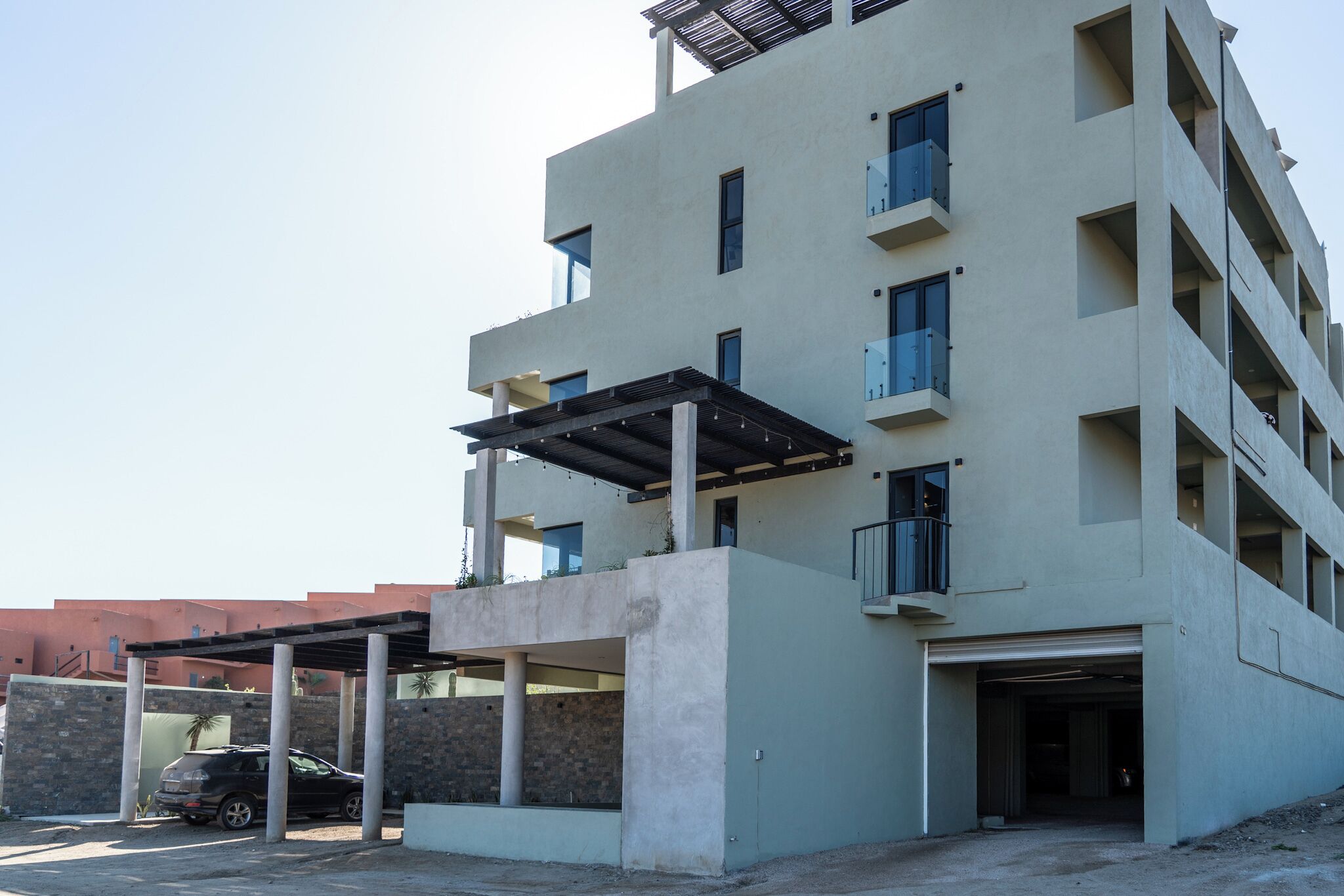 A multi-story building with a covered parking area, a garage, and a balcony.