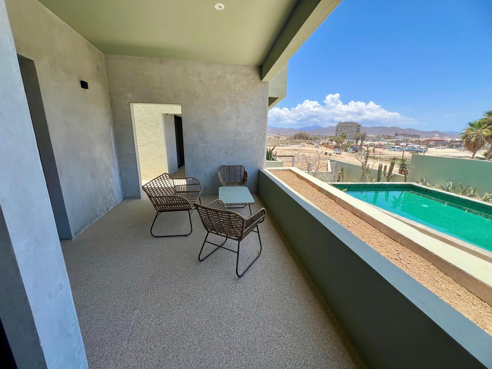 A balcony with a pool, two chairs, and a table.