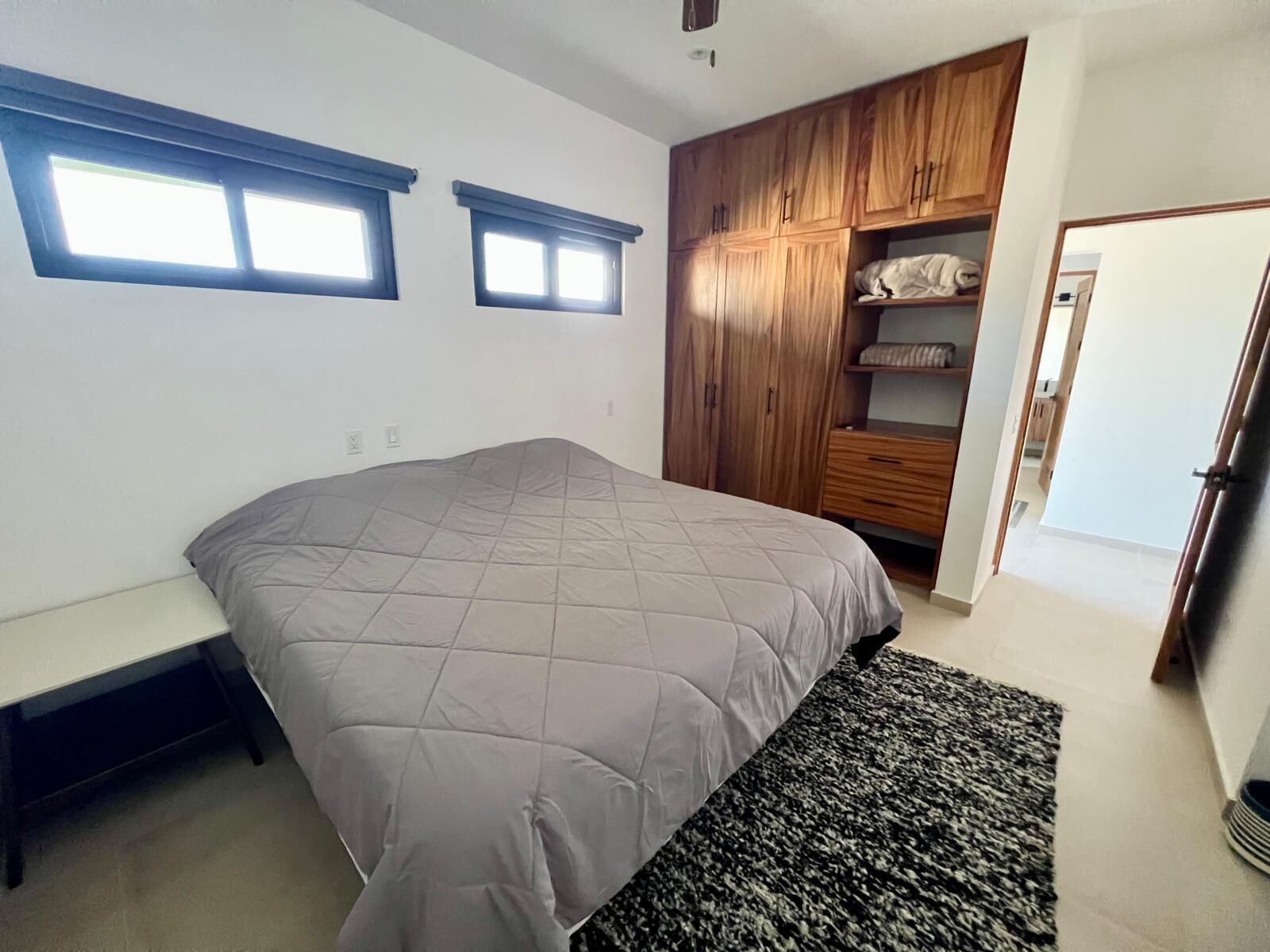 A bedroom with a large bed, a wooden wardrobe, and a bench.
