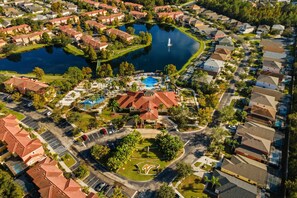 An aerial view of a residential area with a central swimming pool, surrounded by houses and a small lake. - Cozy 3 bedroom Villa at Terra Verde Resort (2513) (Kissimmee)