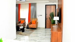Uma sala de estar moderna com dois poltronas, uma mesa de centro, uma televisão e um armário de madeira.