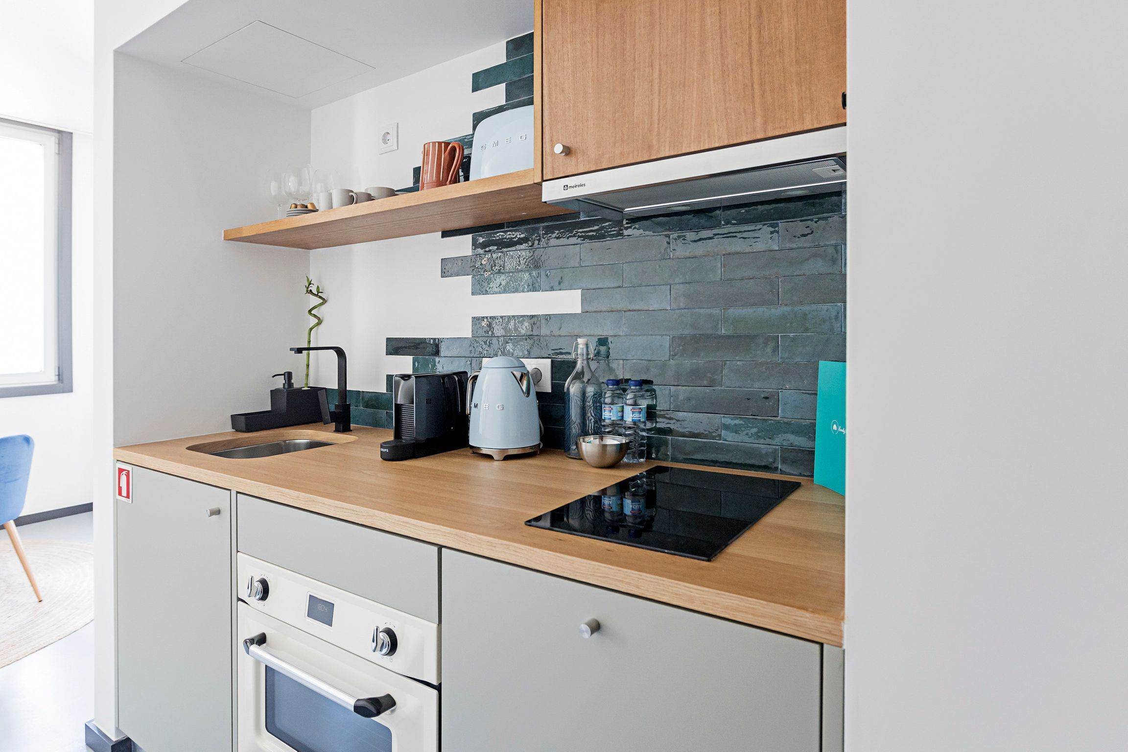 A modern kitchen with a wooden countertop, built-in oven, and a backsplash of dark tiles.