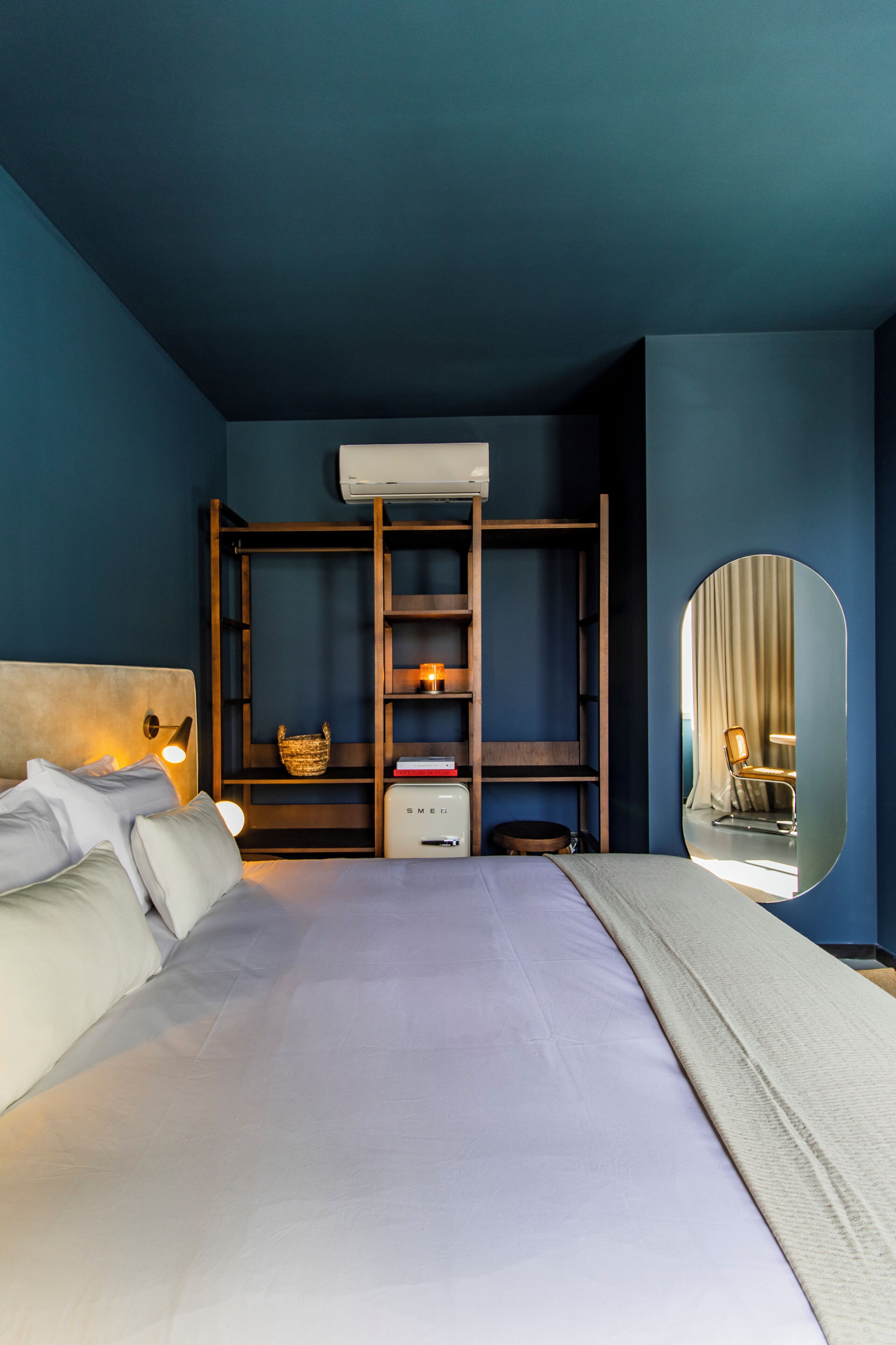 A bedroom with a bed, a wardrobe, a mirror, and a small table.