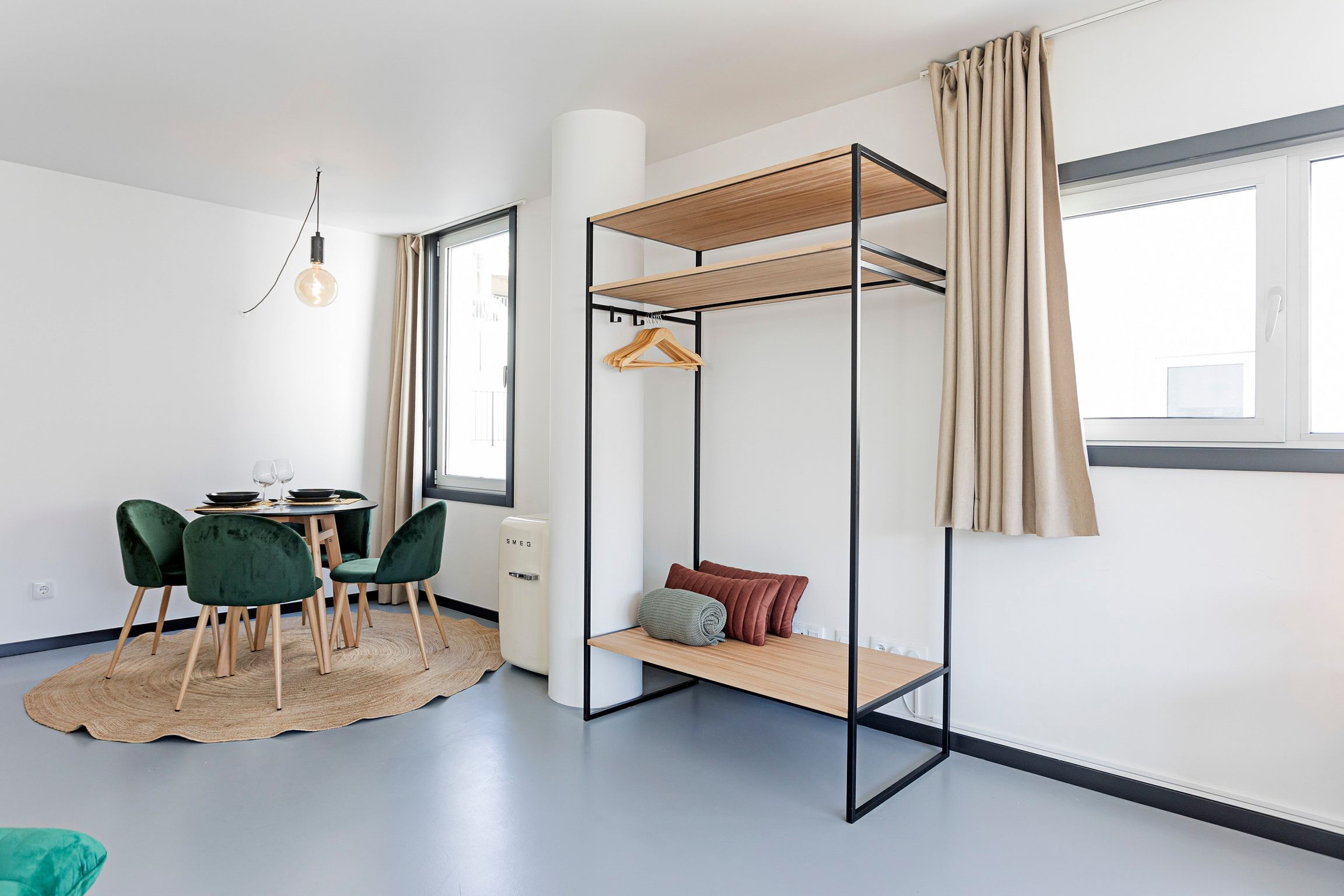 A modern room with a bunk bed, a dining area with a table and chairs, and a large window with curtains.
