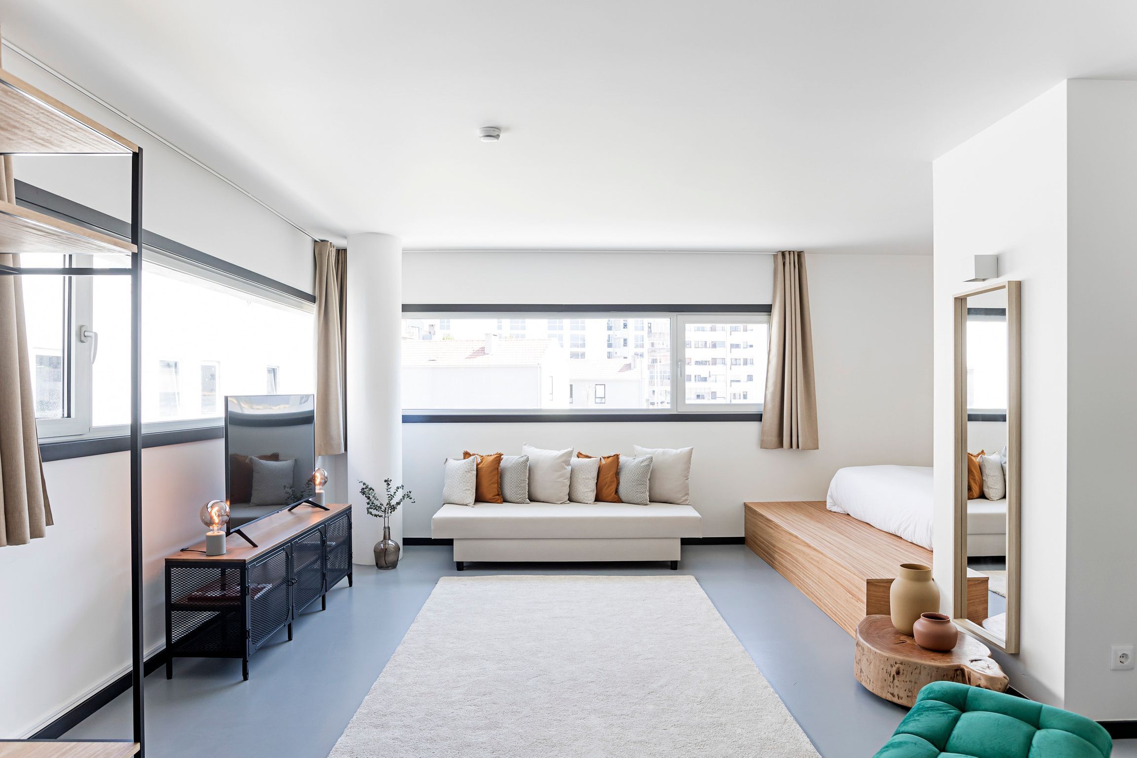 Un dormitorio moderno con un ventanal grande, un sofá, una cama y un escritorio.
