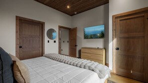 Une chambre à coucher avec un lit, une armoire en bois, un miroir et un tableau accroché au mur.