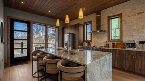 Une cuisine moderne dotée d’un grand îlot central, de tabourets de bar, d’un réfrigérateur et d’une cuisinière.