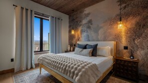 A bedroom with a large bed, a view of the outdoors through a window, and a textured wall. - Rooftop Deck w Fireplace, Pool w/ Grotto, Game Room, Hot Tub, Panoramic Views (Sevierville)