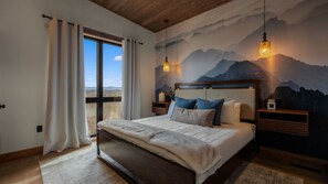 Ein Schlafzimmer mit einem großen Bett, Blick auf Berge durch das Fenster und einer Berglandschaft an der Wand.