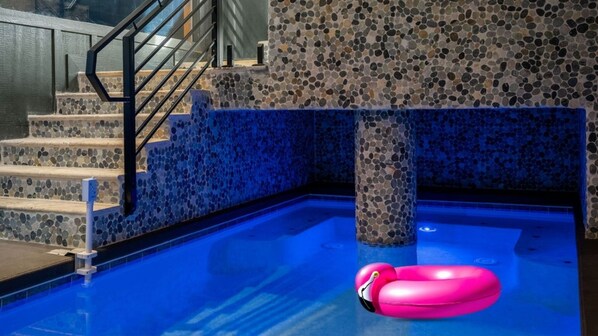 A swimming pool with a pink flamingo float, stairs with mosaic tiles, and a metal handrail. - Rooftop Deck w Fireplace, Pool w/ Grotto, Game Room, Hot Tub, Panoramic Views (Sevierville)