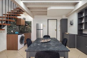 A modern kitchen with a marble countertop, a built-in washing machine, and a staircase with wooden steps. - GuestHost - Charming 50-sqm apartment, perfect for two people, located on the first floor of a historic building.The property is situated in a renowned area right in the historic city center, well connected to all main services.Nearby is Piazza Angelo Ma (Catania)
