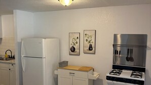A compact kitchen with a white refrigerator, a small cabinet with a wooden countertop, and a white stove. - Delightful, easy living, 1-bedroom apartment with AC in San Antonio (San Antonio)