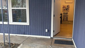 A house with a stone-paved entrance, a covered porch, and a door leading to an interior room with a chair and a table. - Delightful, easy living, 1-bedroom apartment with AC in San Antonio (San Antonio)