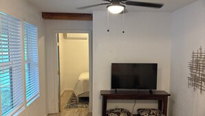 A living room with a ceiling fan, a TV on a wooden stand, and a sofa. - Delightful, easy living, 1-bedroom apartment with AC in San Antonio (San Antonio)