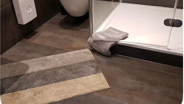 A bathroom with a shower, a toilet, and a towel rack. - Very comfortable apartment in the heart of Cologne city center - Neumarkt (Köln)