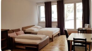 A hotel room with two beds, a sofa, a dining table, and a chair.