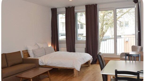 A bedroom with a bed, a sofa, a table, and chairs.