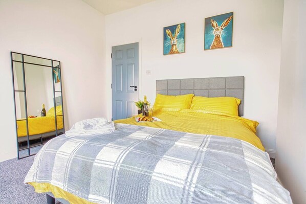 Un dormitorio con una cama, un espejo y dos cuadros en la pared.