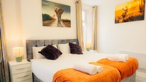 A double bed with two pillows, a nightstand, a lamp, and a painting of a deer on the wall. - Stylish 3-Bed Flat Near Cardiff City Centre & Uni (Cardiff)