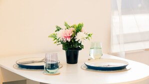 A table with a vase of flowers, two glasses of water, and a fork and knife on a white table. - Stylish 3-Bed Flat Near Cardiff City Centre & Uni (Cardiff)