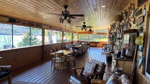 Una terraza de madera con mesas, sillas, un sofá y varios objetos decorativos.