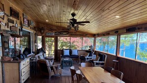 Une cabane en bois comprenant un coin repas, un bar et une grande fenêtre donnant sur un lac.