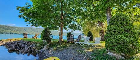 A lakeside setting with a yellow inflatable ring, outdoor seating, and a view of the lake.