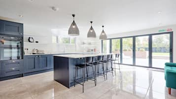 Une cuisine moderne dotée d’un îlot central, de tabourets de bar et de luminaires suspendus.