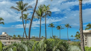 Vista sulla spiaggia con palme e un edificio con balconi che si affaccia sull'oceano.