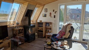 Un accogliente soggiorno in stile loft con camino, pavimento in legno e ampie finestre che si affacciano sull'esterno.