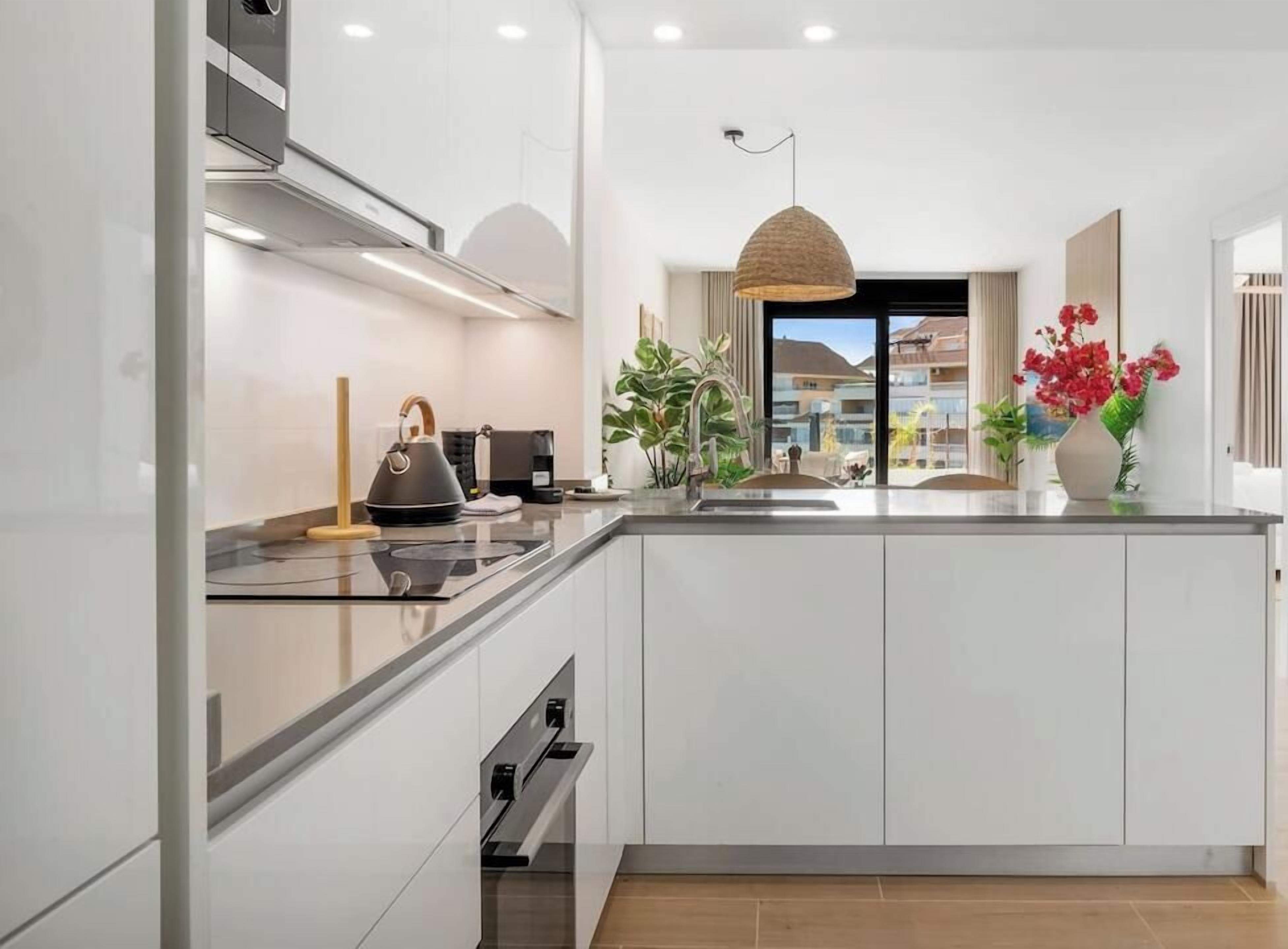 Une cuisine moderne dotée d’un grand îlot central, d’appareils électroménagers intégrés et offrant une vue sur la ville.