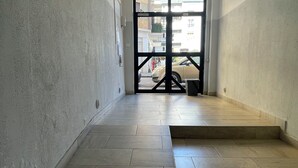 A hallway with tiled flooring leading to a door with a black frame. - Cozy apartment in the center of Cosenza equipped with every comfort (Cosenza)